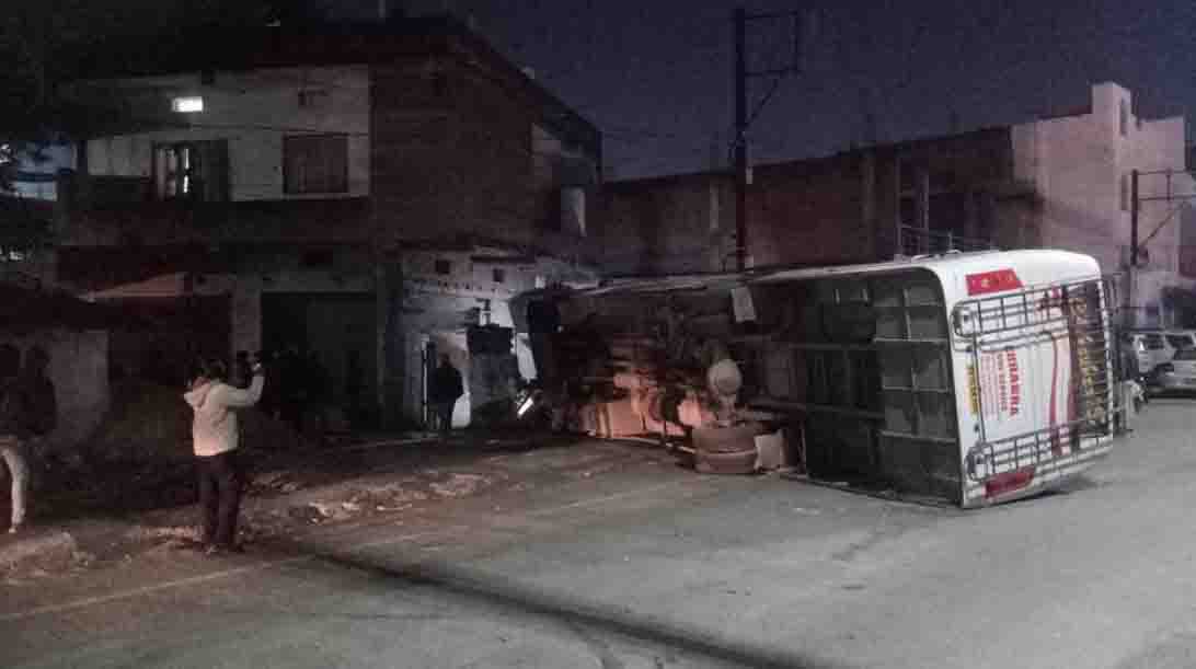 हॉस्पिटल के पास बेकाबू होकर पलटी बस, घर की दीवार को तोड़ा